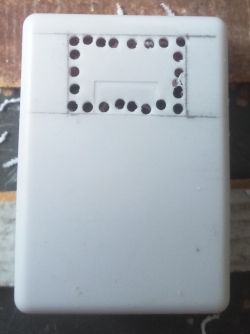 White surface-mount box with hand-drilled holes for a seven-segment display