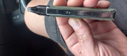 A person holds a long, rectangular electronic device, most likely an electronic cigarette, in their hand.