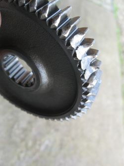 Zbliżenie na uszkodzony zębaty mechanizm z widocznymi uszkodzeniami na zębach.