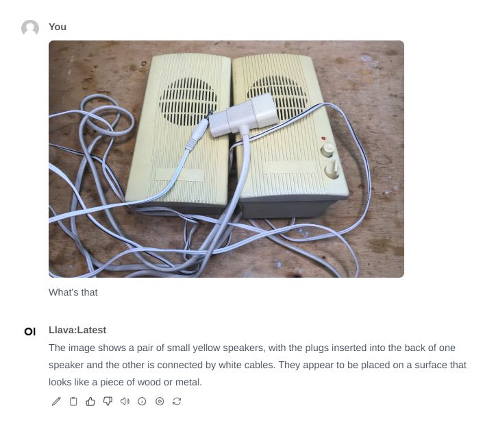 Two Yellow Speakers on a Wooden Surface Two small yellow speakers connected by cables on a wooden surface.