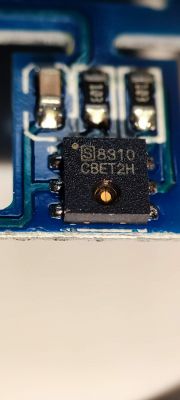 Close-up of an electronic component on a blue printed circuit board with the markings B8310 CBET2H.