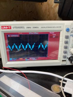 Ekran oscyloskopu pokazujący zniekształcony przebieg sinusa o częstotliwości około 1,2 kHz