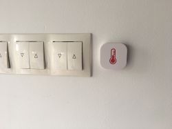 Switch panel and device with a thermometer icon on the wall.