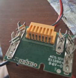 Płytka PCB z żółtym złączem i niepodłączonymi przewodami na drewnianym blacie