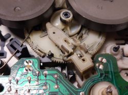 Wnętrze mechanizmu magnetofonu z widocznymi przekładniami i płytką elektroniczną.