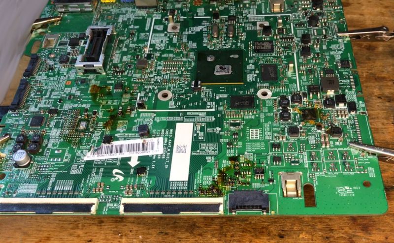 Large green motherboard with many ICs and SMD components on a wooden table