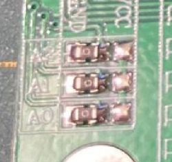 Zbliżenie fragmentu płytki drukowanej z widocznymi elementami elektronicznymi.