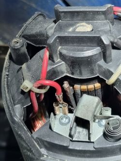 Zbliżenie na wnętrze uszkodzonego urządzenia elektrycznego z widocznymi kablami i złączami.