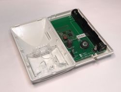 Inside of an electronic motion sensor with visible circuit board and battery holder.