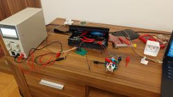 Workspace with an open smart plug and lab power supply on a wooden desk.