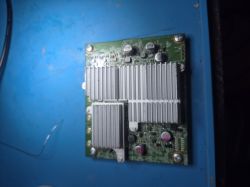 Zielona płytka elektroniczna z dużymi srebrnymi radiatorami na niebieskim tle