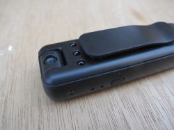 Spy camera with clothing clip Mini spy camera with clip lying on a wooden surface