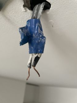 Dwa czarne kable wystające z sufitu, zabezpieczone niebieską taśmą izolacyjną.