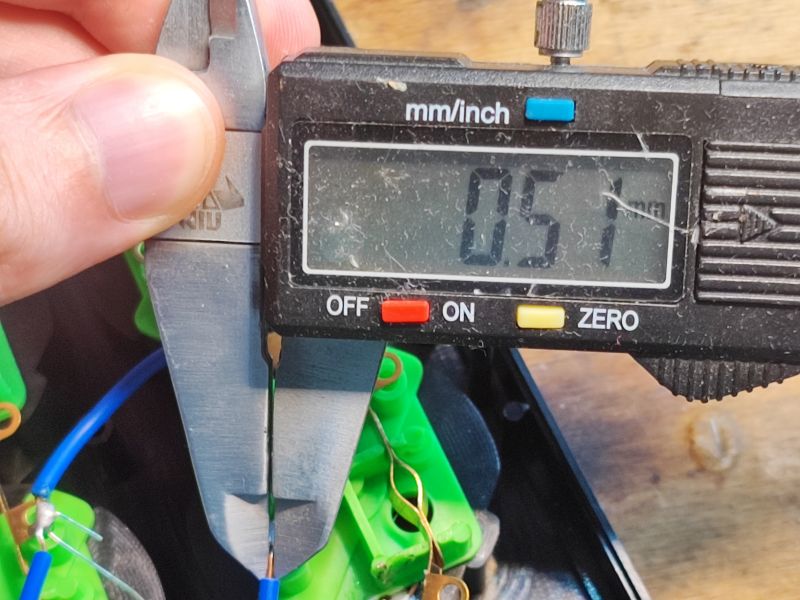 Pomiar średnicy przewodu elektrycznego za pomocą cyfrowego suwmiarki, wynik to 0,51 mm.