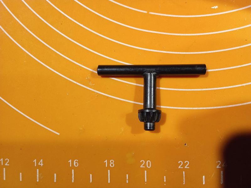 Klucz do uchwytu wiertarskiego na pomarańczowej macie z miarką.