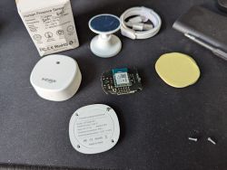 WiFi human presence sensor with exposed circuit board and accessories on a table.