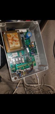 Widok wnętrza otwartej skrzynki sterującej z widocznymi kablami i elementami elektronicznymi.
