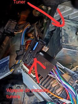 Wnętrze samochodu z pokazanymi podłączeniami elektrycznymi radia i tunera.