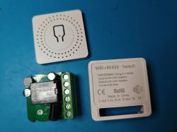 WiFi+RF433 switch module with opened casing on a blue background.