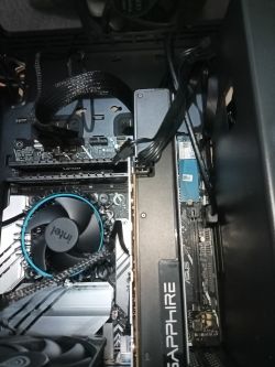 Widok wnętrza komputera z podzespołami, w tym karta graficzna Sapphire i chłodzenie procesora Intel.
