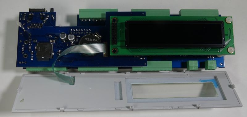 Płytka PCB z modułem wyświetlacza LCD oraz szara obudowa leżące na stole