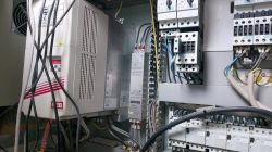 Zdjęcie wnętrza szafki sterowniczej z komponentami elektrycznymi i sterownikami.