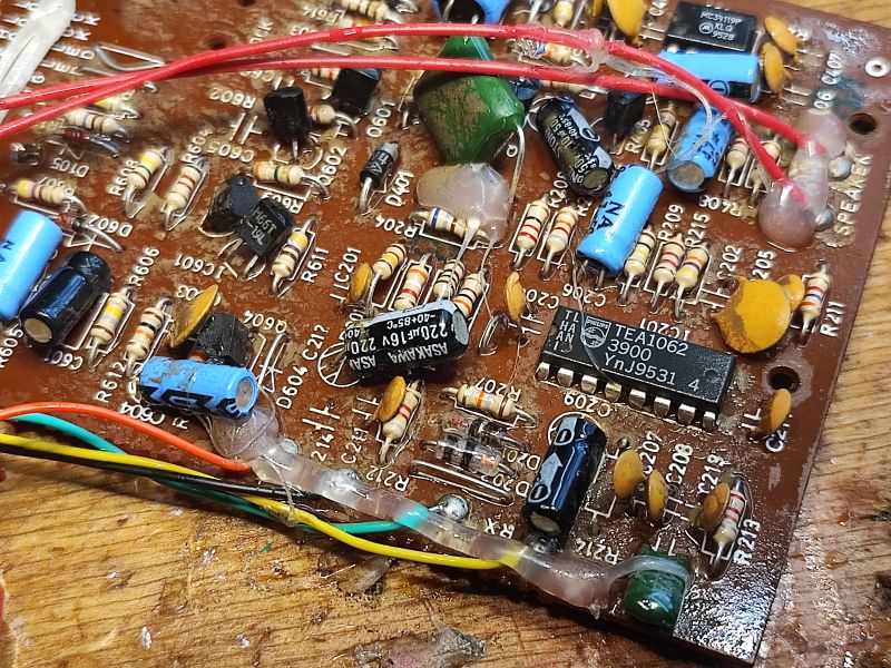 Zbliżenie na wnętrze starego telefonu stacjonarnego z widoczną płytką drukowaną, elementy elektroniczne i okablowanie.