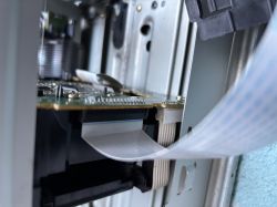 Taśma sygnałowa typu FFC wpięta w złącze na płytce drukowanej wewnątrz urządzenia elektronicznego.
