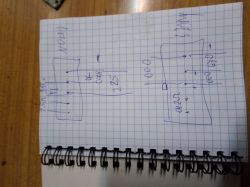 Kartka w kratkę z odręcznymi szkicami technicznymi i cyframi, leżąca na drewnianym blacie.