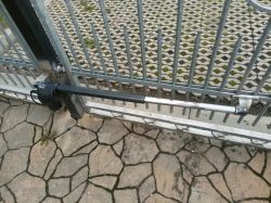 Siłownik bramy skrzydłowej FAAC zamontowany na metalowej bramie.