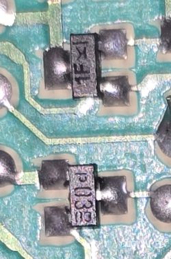 Zbliżenie uszkodzonej płytki PCB z dwoma tranzystorami SOT23 oznaczonymi jako A1SHB i K1.