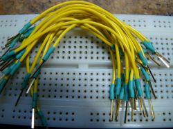 Żółte przewody z niebieskimi koszulkami termokurczliwymi na płytce prototypowej.