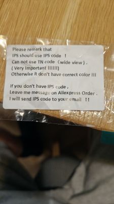 Sticker note about using IPS code instead of TN, on plastic film on a wooden surface