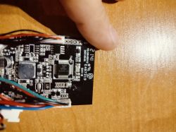 Zbliżenie na płytkę elektroniczną z różnokolorowymi kablami i komponentami na drewnianym tle.