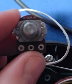 Potencjometr B100K-55 z joysticka Zbliżenie na potencjometr o oznaczeniu B100K-55 trzymany w palcach.