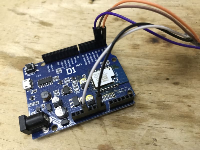 Wi-Fi Programmer Setup on Wemos D1 Board with GPIO Wiring Wemos D1 board with signal wires attached, placed on a wooden surface