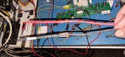 Close-up of electronics workbench with PCB board, wires, and testing probes