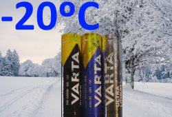 Trzy baterie Varta na tle zimowego krajobrazu z temperaturą -20°C.
