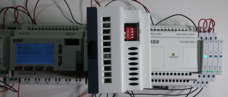 Panel sterowania automatyki przemysłowej z wyświetlaczem LCD i modułami rozszerzającymi, podłączonymi przewodami.