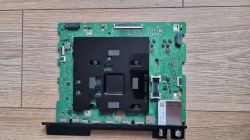 Płyta główna telewizora Samsung na podłodze; zielony PCB z czarną osłoną i złączami na dole.
