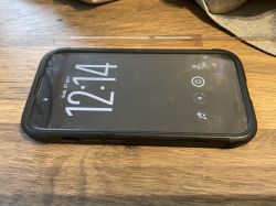 Smartfon w pancernym etui leżący ekranem do góry na drewnianym stole