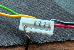 Close-up of white connector with five colored wires attached to exposed pins