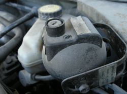 Zbliżenie na element mechaniczny pod maską samochodu.