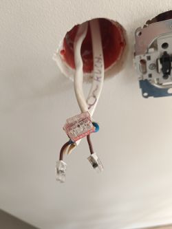 Wnętrze puszki elektrycznej z brązowymi przewodami podłączonymi do złączki.