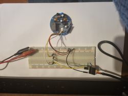 PCB connected by wires to a breadboard; alligator clips on the left, a connector and cable on the right