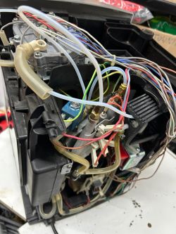 Wnętrze ekspresu DeLonghi z widocznymi przewodami, wężykami i komponentami elektrycznymi