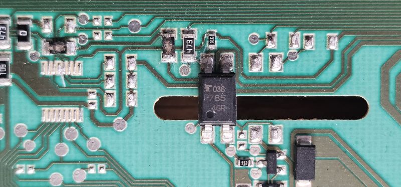 Zbliżenie na fragment zielonej płytki PCB z elementami elektronicznymi i oznaczeniami