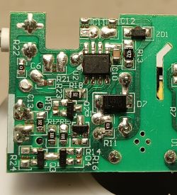 Zbliżenie na płytkę PCB z układami scalonymi, rezystorami i oznaczeniami elementów.