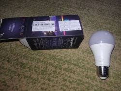 Ewelink SMART A60 bulb next to an open box on a carpet.