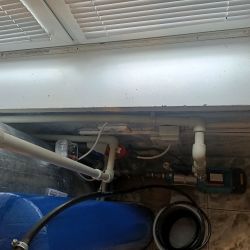 Instalacja wodna z widocznymi rurami i pompą w pomieszczeniu gospodarczym.